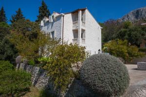 an old white house on a hill with bushes at Apartments Silence in Mlini