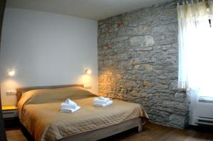 a bedroom with a stone wall and a bed with towels at Guesthouse Bale in Bale