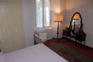 a bedroom with a bed and a lamp and a chair at Affittacamere Trattoria Della Cascata in Oggebbio