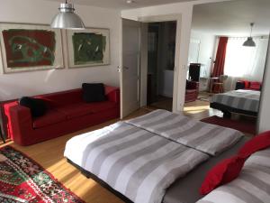 ein Schlafzimmer mit einem großen Bett und einem roten Sofa in der Unterkunft Nickhof B&B Resort in Inzigkofen