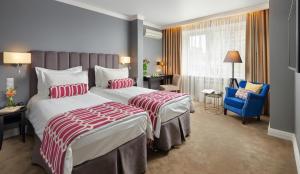 a hotel room with two beds and a blue chair at Easy Room in Nizhny Novgorod