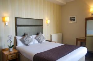 a hotel room with a large white bed with pillows at Kings Hotel in Brighton & Hove