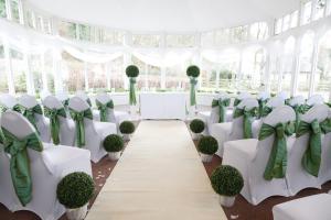 un salón de bodas con sillas y mesas blancas y arcos verdes en Kingswood Hotel, en Burntisland