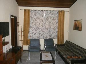 a living room with a couch and chairs in front of a window at Kitnet Penedo in Penedo