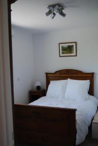 una camera da letto con un letto con lenzuola bianche e un ventilatore a soffitto di Ramier a Giverny