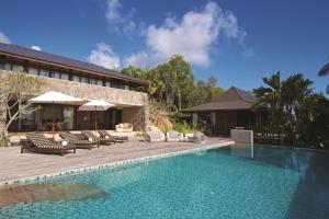 a swimming pool with lounge chairs and a resort at Four Seasons Resort Seychelles in Baie Lazare Mahé
