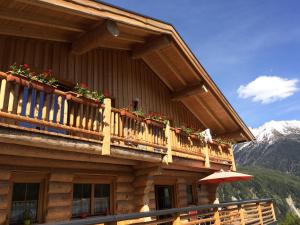 a building with a balcony with flowers on it at Holzberghof in Umhausen