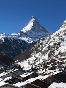 une montagne recouverte de neige avec une ville et des bâtiments dans l'établissement Chalet Guggenbiel, à Zermatt