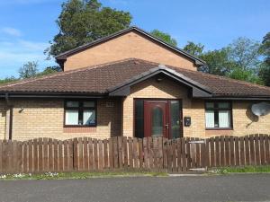 a brown brick house with a wooden fence at Dingieshowe Cottage in Lennoxtown