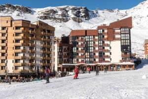 people on skis in the snow in front of a hotel at Nazca C8 in Val Thorens