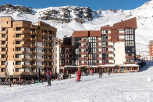 persone sugli sci nella neve di fronte a un hotel di Nazca C8 a Val Thorens