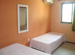 um quarto com 2 camas, um espelho e uma janela em Pousada Vianna's em Fortaleza
