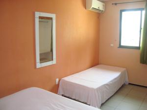 Duas camas num quarto com um espelho e uma janela em Pousada Vianna's em Fortaleza