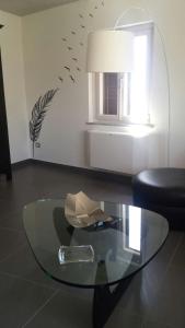 un tavolo in vetro in soggiorno con uccelli sulla parete di Alessi Suites & Studio a Mazzarino