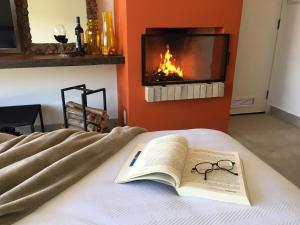 a book and glasses on a bed with a fireplace at Latitude Lodge in Cunha