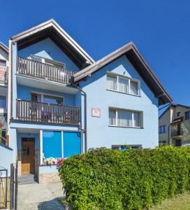 a blue house with a balcony and bushes at Niebieska Willa in Jastarnia