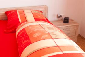 Plankstadt的住宿－科爾公寓，一张带红色棉被和木床头柜的床