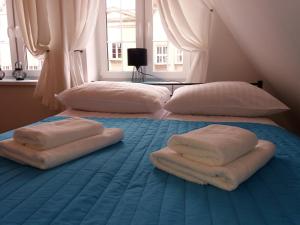 two beds with towels on top of a blue bed at H&T Apartament przy Starym Żurawiu in Gdańsk