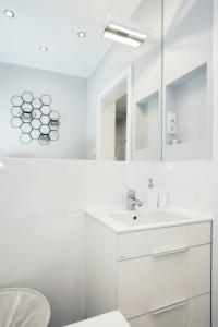 a white bathroom with a sink and a mirror at Apartament Kowalska in Gdańsk