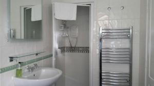 a white bathroom with a shower and a sink at Pencubitt House in Liskeard