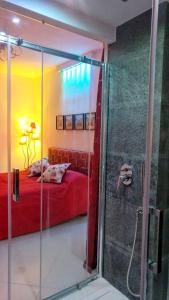 um chuveiro de vidro num quarto com uma cama vermelha em MaLu' B&B em Sorrento