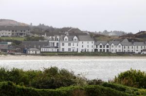 a large white house sitting next to a body of water at No. 1 Charlotte Street in Port Ellen