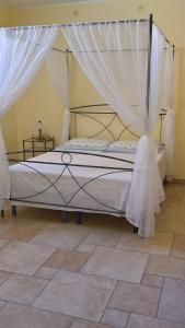 1 dormitorio con cama con dosel y cortinas blancas en B&B Verardo, en Specchia