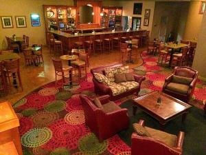 a living room with a large rug with chairs and a bar at Days Inn by Wyndham Warren in Warren