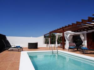 uma piscina com uma pérgula ao lado de uma casa em Happy Villa con piscina privada em Playa Blanca