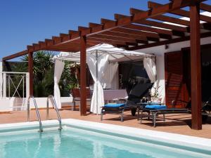 uma piscina com uma pérgula de madeira e uma casa em Happy Villa con piscina privada em Playa Blanca