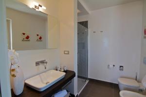 a bathroom with a sink and a toilet and a mirror at Tenuta Del Poggio Antico in Ischia