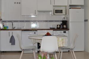 トレ・デル・マールにあるApartamento Ancla 26の白いキャビネット、テーブルと椅子付きのキッチンが備わります。