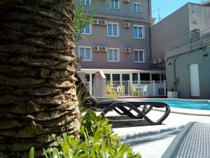 a bench in front of a building with a swimming pool at Hotel Le Majestic Canet plage in Canet-en-Roussillon