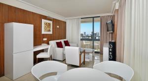 um quarto com cadeiras brancas, uma mesa e uma televisão em Melia Benidorm em Benidorm