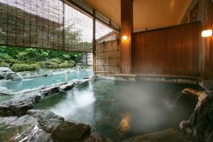 a hot tub in a room with a river at Shouhakutei Azumaso in Tendo