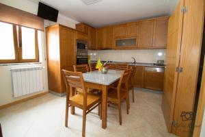 a kitchen with wooden cabinets and a table and chairs at Casa do Telheiro in Sabugueiro