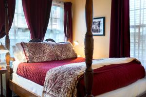 1 dormitorio con cama con dosel y cortinas rojas en The Blue60 Marigny Inn en Nueva Orleans