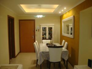 a dining room with a table and white chairs at Apartamento Das Palmeiras in Porto Alegre