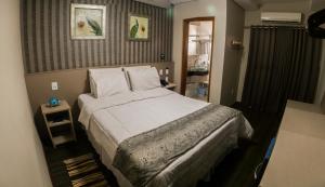 a bedroom with a large bed with white sheets and pillows at Hotel Santo Graal in Aparecida