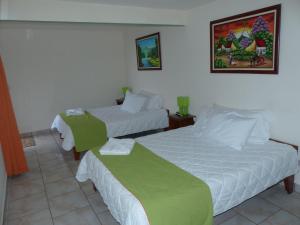 a hotel room with two beds with green sheets at Mountain Faro Hotel in Monteverde Costa Rica