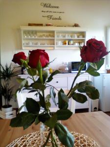 un jarrón con dos rosas sentado en una mesa en Dimora San Lazzaro B&B, en Lucca