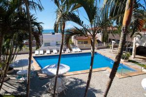 a swimming pool with palm trees and lounge chairs at Hotel Nova Guarapari in Guarapari