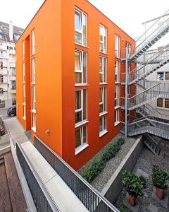 ein orangefarbenes Gebäude mit einer Treppe davor in der Unterkunft Internationales Studierendenhotel in Stuttgart