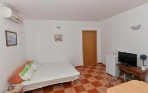 Dieses weiße Zimmer verfügt über ein Bett und einen Flachbild-TV. in der Unterkunft Apartments Mila - Mala Duba in Živogošće