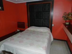 um quarto com uma cama com uma parede laranja em Hotel Guayaquil em Santiago