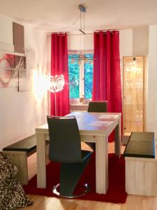 comedor con mesa y cortinas rojas en Ferienwohnung Döllinger Messe Fränkisches Seenland, en Schwabach