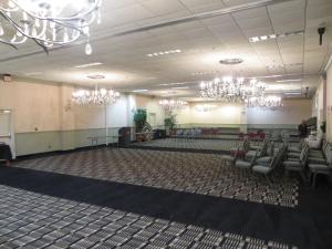 um quarto amplo com cadeiras e lustres em Olive Tree Hotel and Banquet halls em Jackson