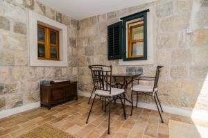 Studio apartment Antica في سيليبي: طاولة وكراسي في غرفة مع جدران حجرية