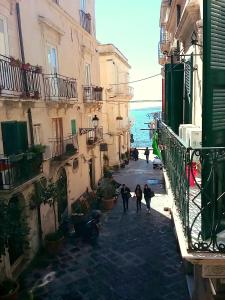 a group of people walking down a street next to buildings at La casa di Adele in Syracuse