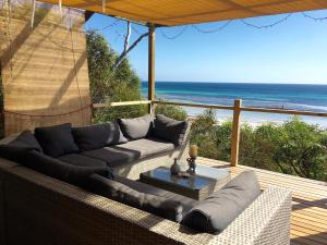 a patio with a couch and a table and the ocean at The Beach Shack in Emu Bay